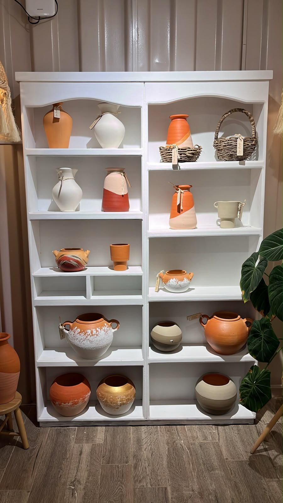 Vitrina blanca con vasijas y jarrones de cerámica artesanal en tonos terracota dentro de Casa Rosada