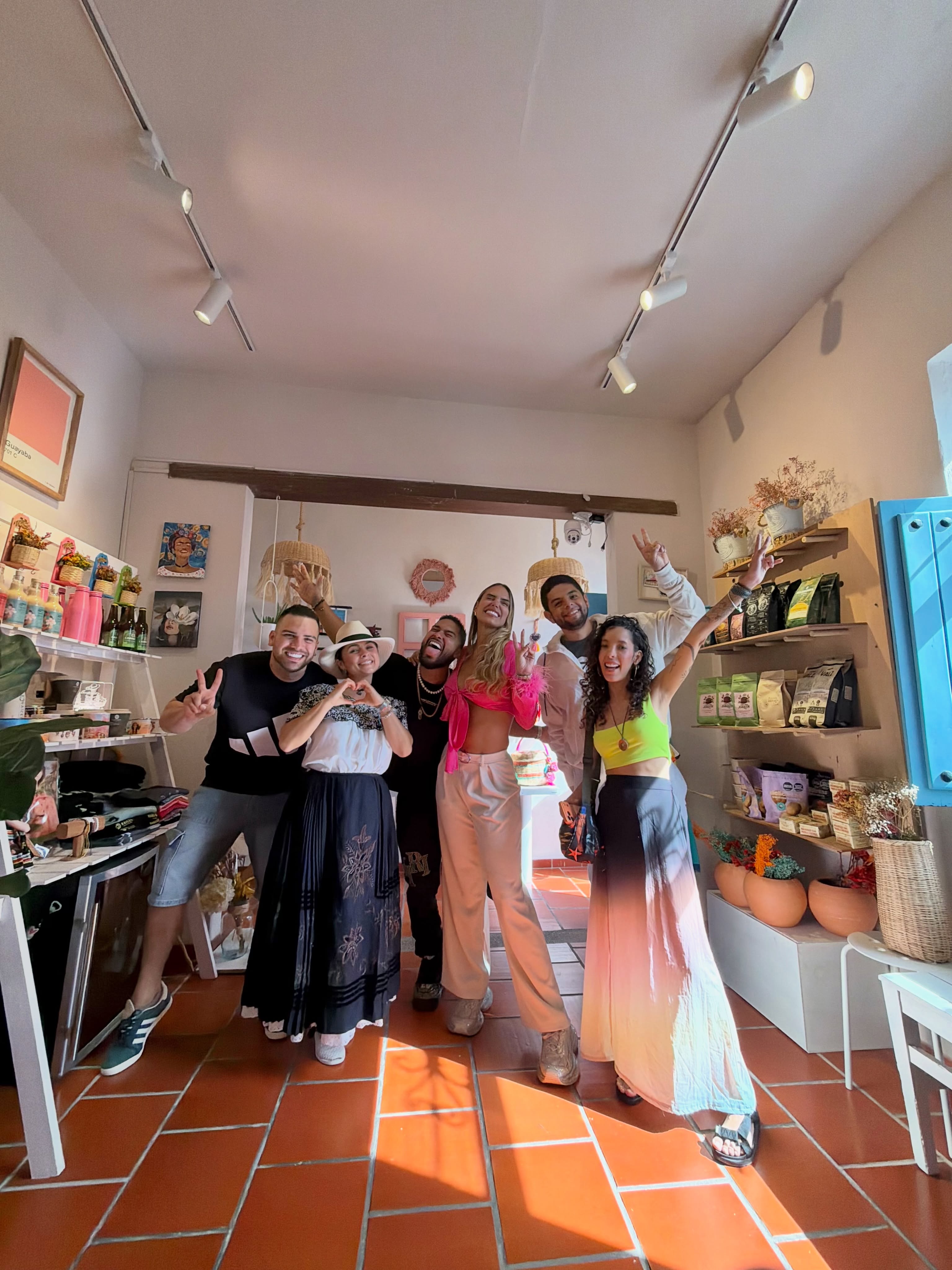 Grupo de amigos disfrutando y posando dentro de la tienda Casa Rosada, junto a los estantes de café y artesanías